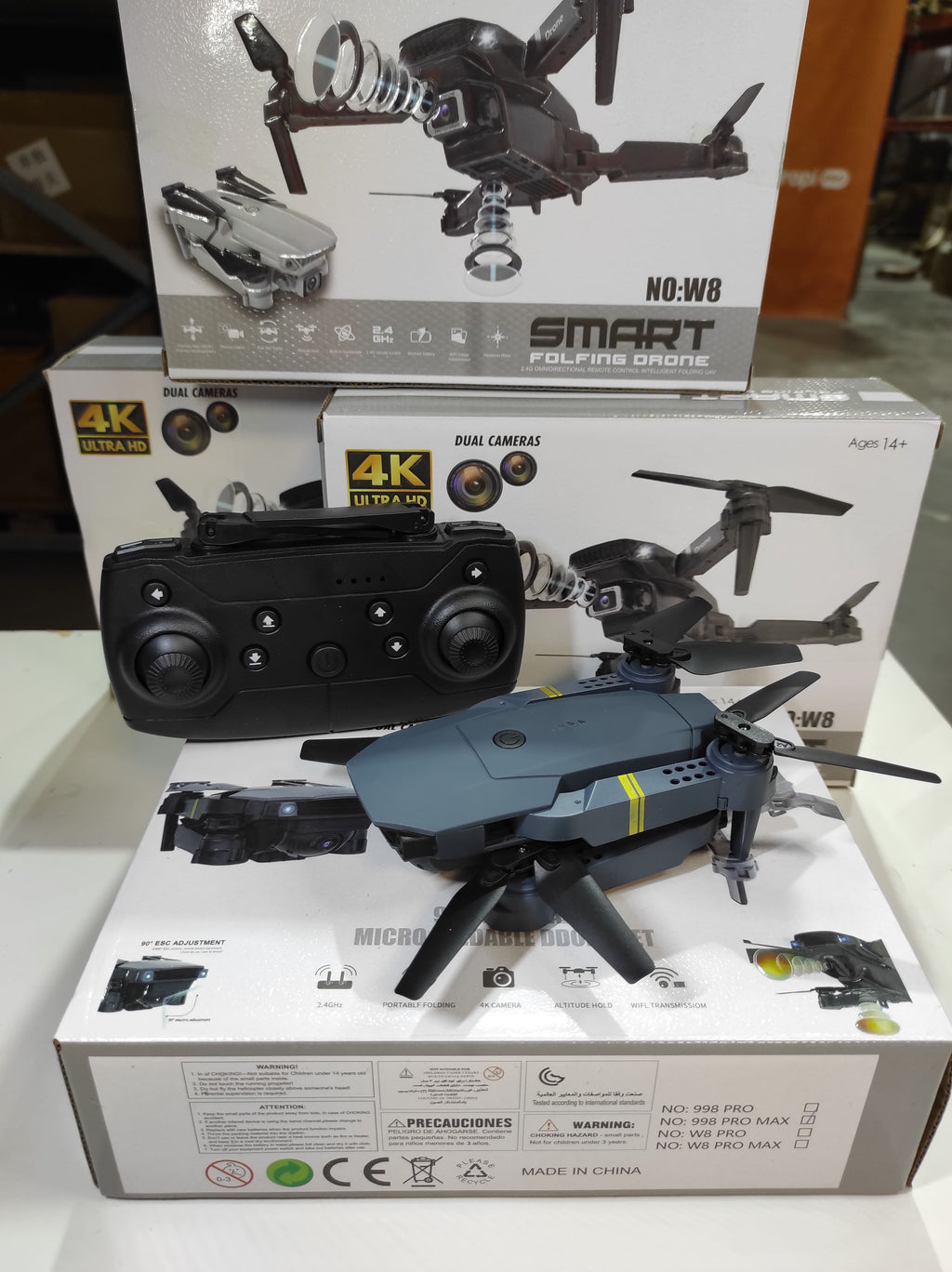 Dron doble cámara 4K con control remoto sobre cajas, ideal para volar en interiores.
